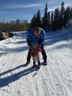 A man and child on skis in the snow.