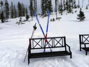 A bench with skis on it in the snow.