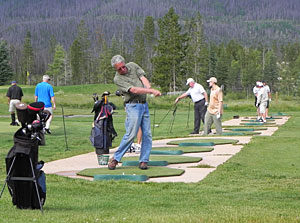 A man swinging at a golf ball on the green.